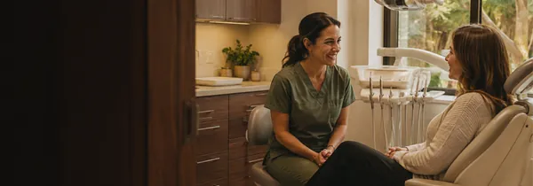 A dental hygienist talking with a patient in the treatment room